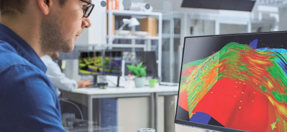 A picture of a man at a computer looking at a three-dimensional rendering of oil deposits